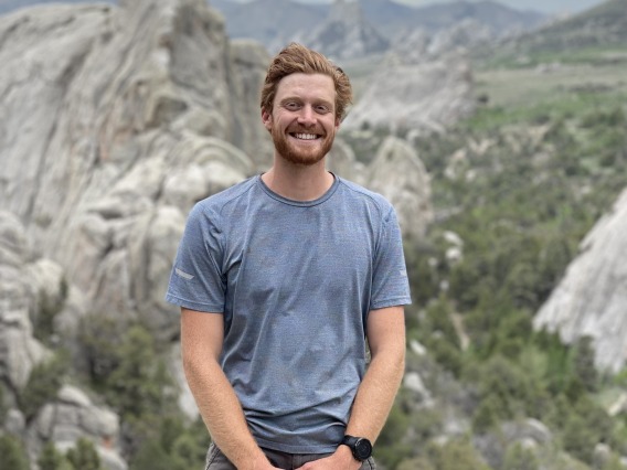 Jacob Stuivenvolt Allen standing for a photo in front of mountains at a high altitude.