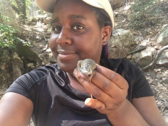 Earyn McGee holding a lizard in a forest.