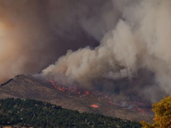 A large amount of smoke coming from a fire on a mountain range.