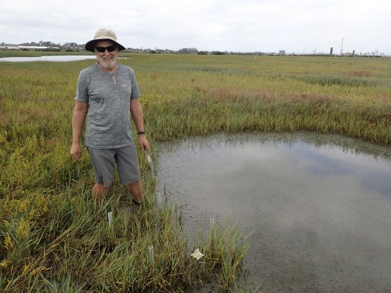 Richard Ambrose standing next to a pond in the middle of a field