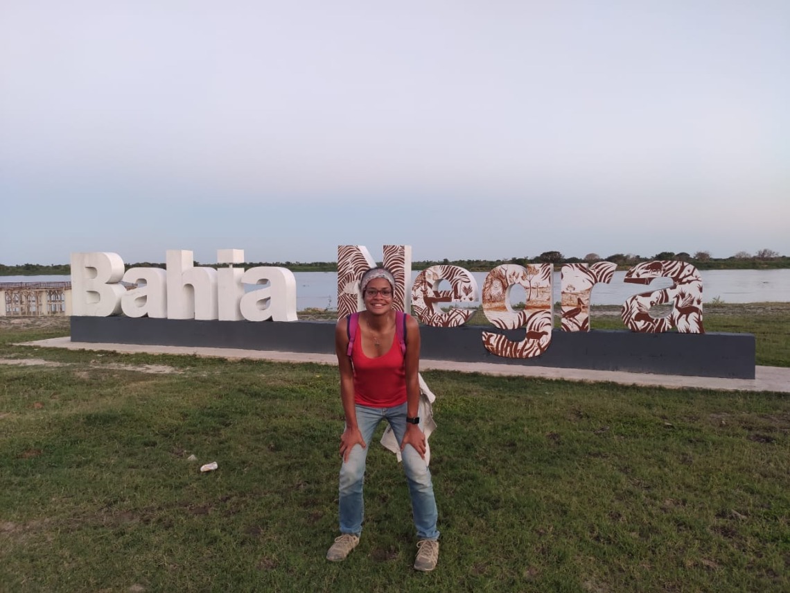 Sonia Delphin-Perez standing with hands on knees in front of Bahia Negra sign