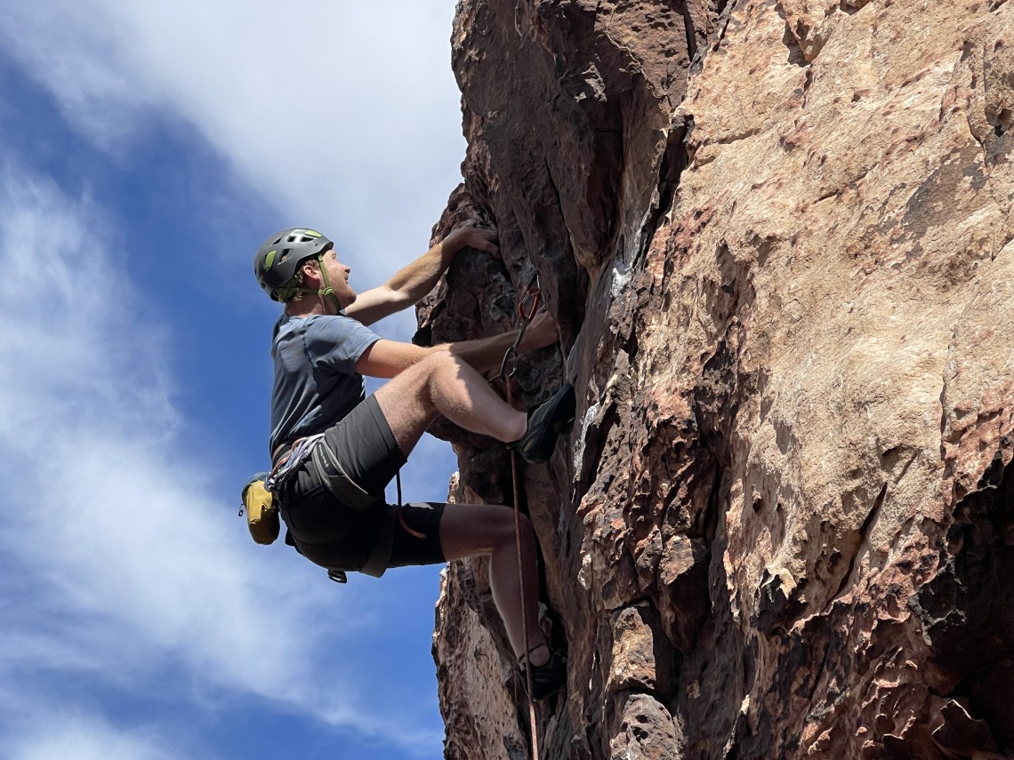 Jacob Stuivenvolt Allen rock climbing on the side of a mountain.