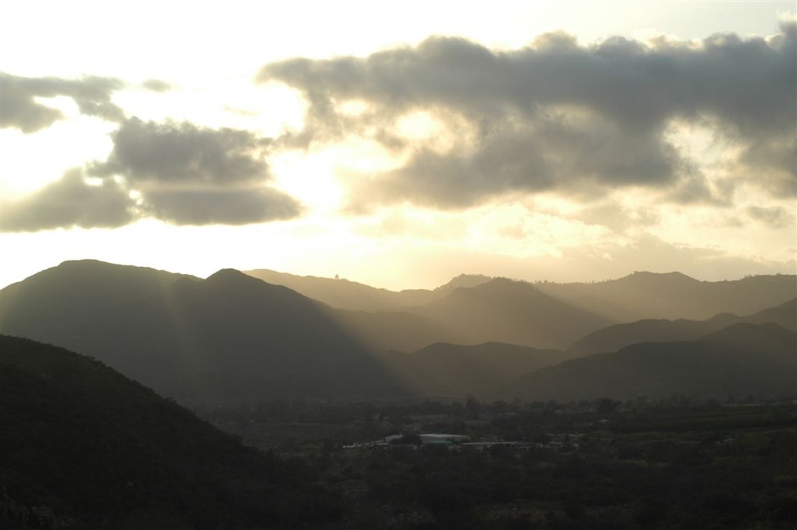 The sunset through a cloudy sky over mountains in the Pala Indian Reservation.