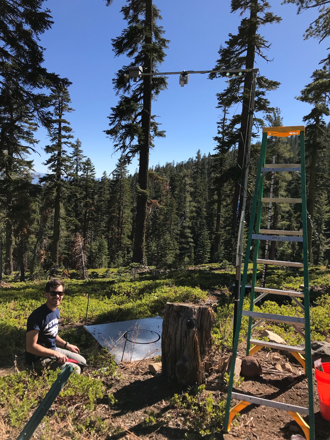 Josh Sturtevant in a mountain forest setting up research equipment.
